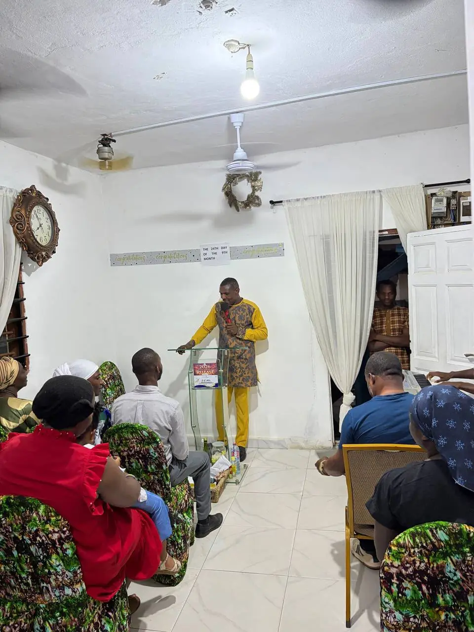A minister preaching from the glass pulpit to the seated congregation